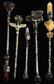 Five ornate silver-toned crystal and gemstone wands arranged vertically on a dark background. The wands feature unique pendants including a heart-shaped stone, angel wings, a pink stone, a dark cat skull, and a yellow stone with floral detailing.