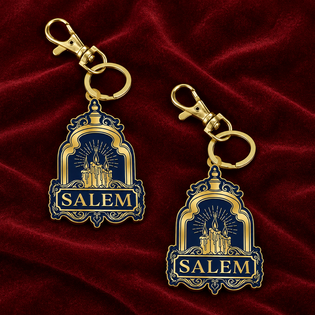 Two gold metal keychains with navy blue enamel charms featuring the word 'SALEM' and a castle illustration, shown on a light gray background with the text 'METAL KEYCHAIN' at the top right.