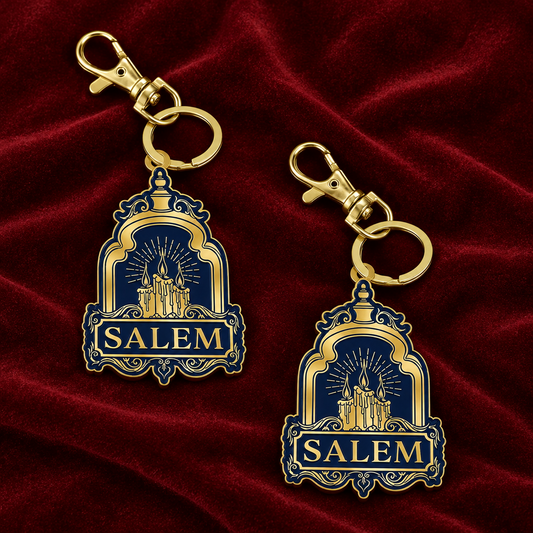 Two gold metal keychains with navy blue enamel charms featuring the word 'SALEM' and a castle illustration, shown on a light gray background with the text 'METAL KEYCHAIN' at the top right.
